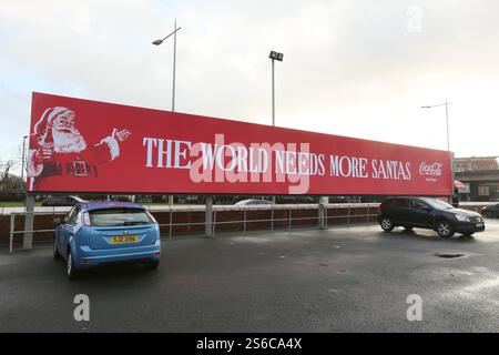 Belfast, Irlande du Nord - décembre 2024 - Un grand panneau Coca Cola avec une photo du Père Noël et les mots « le monde a besoin de plus de santas » visibles depuis une rue du centre-ville de Belfast pendant les derniers jours avant Noël. Banque D'Images