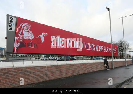 Belfast, Irlande du Nord - décembre 2024 - Un grand panneau Coca Cola avec une photo du Père Noël et les mots « le monde a besoin de plus de santas » visibles depuis une rue du centre-ville de Belfast pendant les derniers jours avant Noël. Banque D'Images