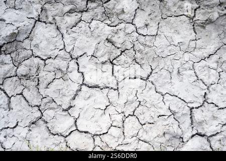 Gros plan de boue séchée et craquelée formant des motifs naturels complexes. Cette surface texturée constitue un fond ou une superposition idéal pour les projets créatifs. Banque D'Images