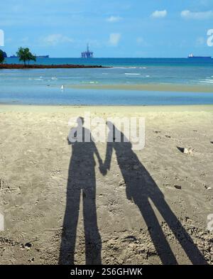 couple d'ombres tenant la main à la plage de sable Banque D'Images