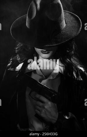Silhouette d'une détective féminine dans un manteau et un chapeau avec un pistolet dans ses mains. Un livre drame noir portrait dans le style des détectives des années 1950 Banque D'Images