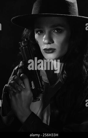 Silhouette d'une détective féminine dans un manteau et un chapeau avec un pistolet dans ses mains. Un livre drame noir portrait dans le style des détectives des années 1950 Banque D'Images