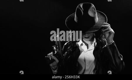 Silhouette d'une détective féminine dans un manteau et un chapeau avec un pistolet dans ses mains. Un livre drame noir portrait dans le style des détectives des années 1950 Banque D'Images