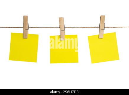 Trois notes adhésives jaune vif sont coupées à une ficelle avec des pinces à linge en bois, créant un affichage joyeux et organisé. Banque D'Images