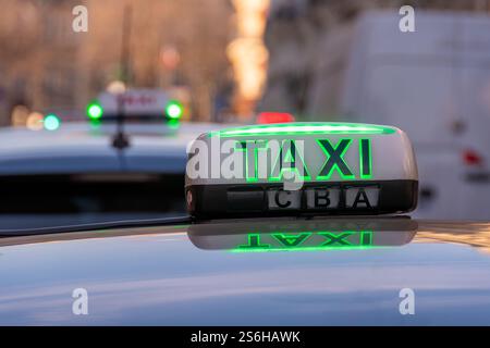 Panneau lumineux de toit avec le mot 'TAXI' allumé en vert (taxi gratuit) fixé à un véhicule stationné à une station de taxi dans une rue de Paris, France Banque D'Images