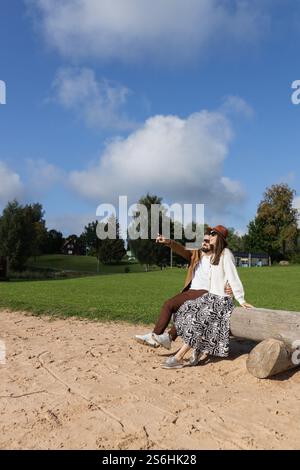 Heureux couple jeune adulte assis sur une bûche d'arbre en bois et souriant Banque D'Images