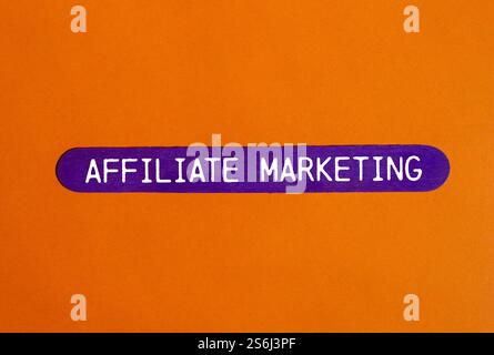 Message de marketing d'affiliation écrit sur bâton en bois violet avec fond orange. Symbole conceptuel de marketing d'affiliation. Copier l'espace. Banque D'Images