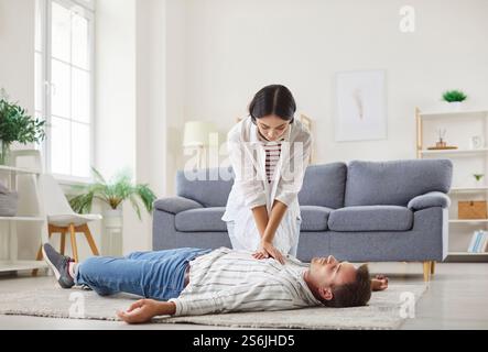 Jeune femme faisant la RCP sur un homme inconscient allongé sur le sol à la maison. Banque D'Images