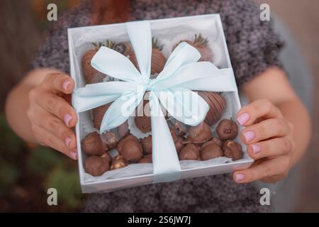 fille tient une main dans une boîte cadeau festive. Photo de haute qualité Banque D'Images