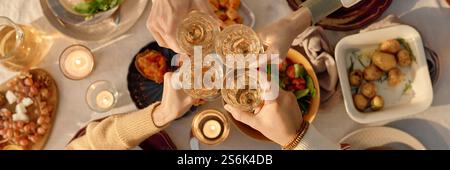 Bannière de site Web avec vue descendante de personnes méconnaissables tapissant des verres avec du champagne au-dessus de la table de fête servie avec de délicieux plats Banque D'Images