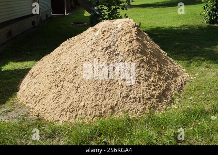 Un tas de sable de construction sur un fond d'herbe verte Banque D'Images