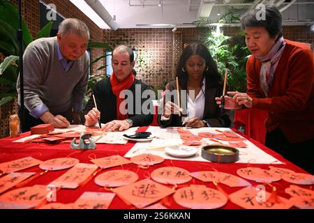 Pékin, Chine. 17 janvier 2025. Les résidents étrangers apprennent la calligraphie chinoise lors d'une réunion communautaire dans le sous-district de Zuojiazhuang du district de Chaoyang à Pékin, capitale de la Chine, le 17 janvier 2025. Les résidents chinois et étrangers du sous-district de Zuojiazhuang à Pékin ont pris part à diverses activités culturelles lors d'une réunion communautaire qui s'est tenue vendredi avant le Festival du printemps. Crédit : Jin Liangkuai/Xinhua/Alamy Live News Banque D'Images
