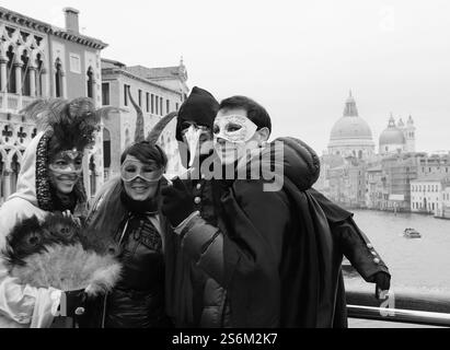 VENISE, ITALIE - 14 FÉVRIER 2015 : touristes en masque photographiés au pont de l'Accademia avec vue sur le Grand canal. Photo historique noir et blanc Banque D'Images