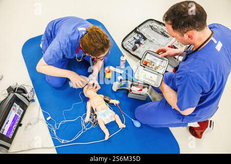PRODUCTION - 17 janvier 2025, Hesse, Francfort/M. : Michelle Wunderer, assistante en anesthésie, ventile un bébé simulé avec une poche de réanimation lors d'une formation aux urgences pédiatriques, tandis que Sven Düwel, du service d'incendie professionnel, prend un médicament d'un cas. Depuis le début de 2025, une formation obligatoire est dispensée aux nouveau-nés et aux urgences pédiatriques pour les services d'urgence en Hesse. Photo : Lando Hass/dpa Banque D'Images