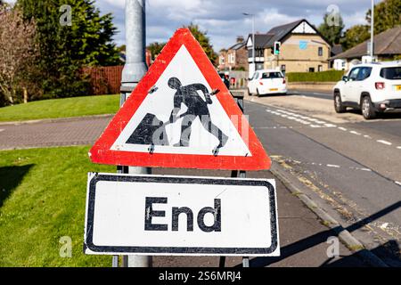 Vue paysage d'un panneau triangulaire de travaux routiers avec une bordure rouge est affiché bien en évidence sur le côté d'une route Banque D'Images