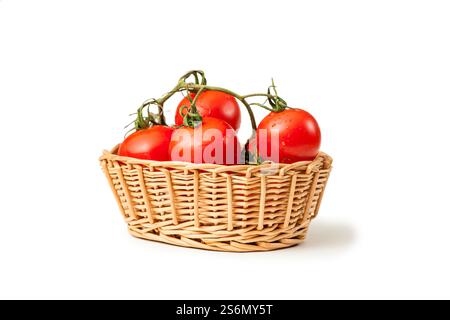 Vue en bas angle d'un panier en osier avec des tomates de vigne (lat : Solanum lycopersicum) sur fond blanc de studio avec ombre. Banque D'Images