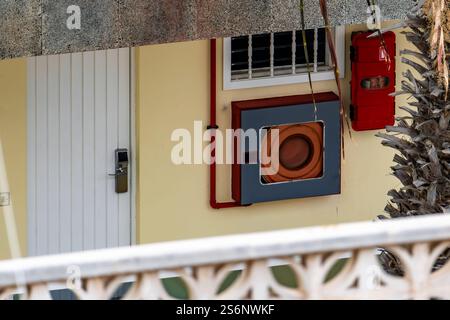 Une voiture rouge est suspendue à une fenêtre. La voiture est rouge et a une bouche d'incendie sur le dessus Banque D'Images