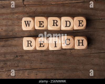 Dés en bois avec les mots allemands s'enrichir sur une table en bois Banque D'Images