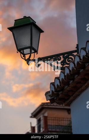 Lampe de rue vintage contre le ciel vibrant de coucher de soleil et les détails architecturaux Banque D'Images