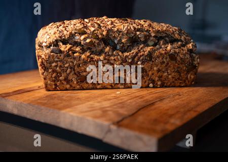 Pain à grains entiers fraîchement cuit sur une surface de travail en bois. Photographie culinaire. Contexte pour une nutrition saine. Gros plan. Banque D'Images