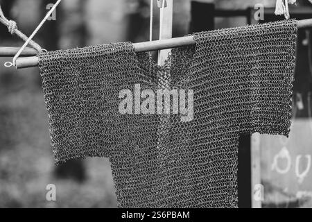 Une photo en noir et blanc d'une veste en métal accrochée à une corde. La veste est faite de métal et a une texture en treillis. La photo a une sensation vintage à Banque D'Images