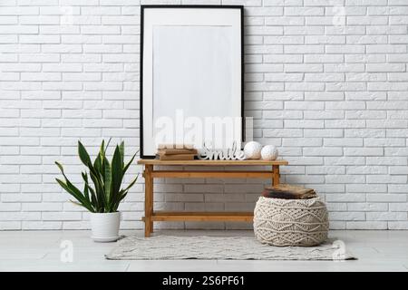 Pile de vieux livres, photo et statuettes sur le banc près du mur de briques blanches dans la chambre Banque D'Images