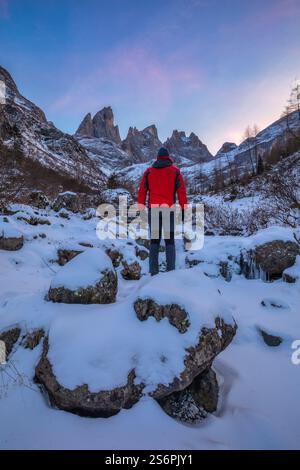 Randonneur dans la vallée isolée de Focobon au crépuscule, dominé par les flèches du Focobon, côté nord-est du groupe pale di San Martino, Dolomites, municipalité de Falcade, province de Belluno, Vénétie, Italie Banque D'Images