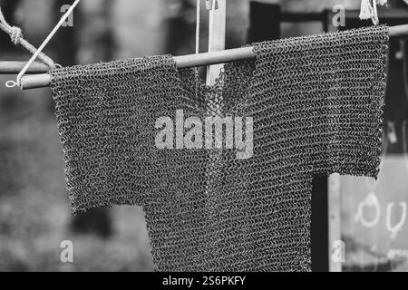 Une photo en noir et blanc d'une veste en métal accrochée à une corde. La veste est faite de métal et a une texture en treillis. La photo a une sensation vintage à Banque D'Images
