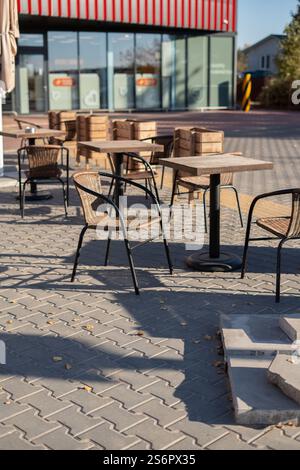 Photo coin salon extérieur avec chaises en osier et tables en bois devant un café moderne à façade vitrée, invitant à la détente et à l'interaction sociale Banque D'Images