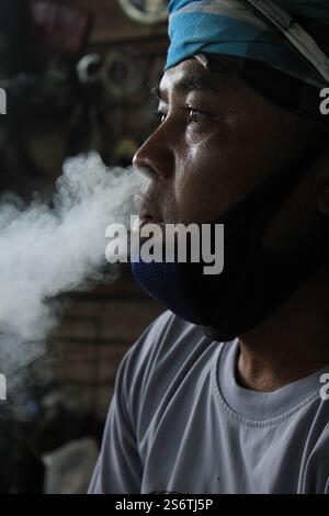 Un travailleur migrant birman aime une cigarette après une longue journée de travail dans les champs près de Mae Sot, en Thaïlande Banque D'Images