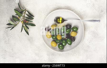 Un mélange d'olives, une variété de Chalkidiki, verdi giganti et Kalamata, sur une assiette avec une cuillerée d'huile d'olive, vue de dessus, pas de gens Banque D'Images