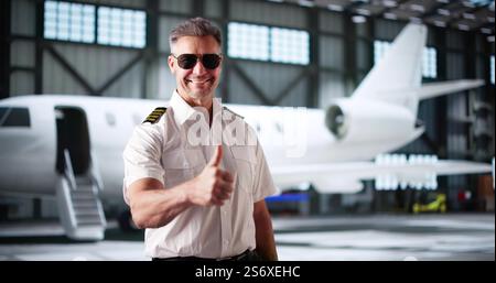Pilote de capitaine de jet privé en uniforme faisant un geste Thumbs Up Banque D'Images