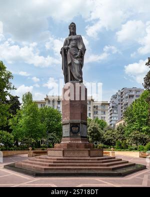 Bakou, Azerbaïdjan - 5 mai 2024 : Grande statue de Nizami Ganjavi dans le parc Nizami Ganjavi. Le poète tient un livre, symbolisant sa contribution à la littérature persane, au milieu d'une végétation luxuriante Banque D'Images