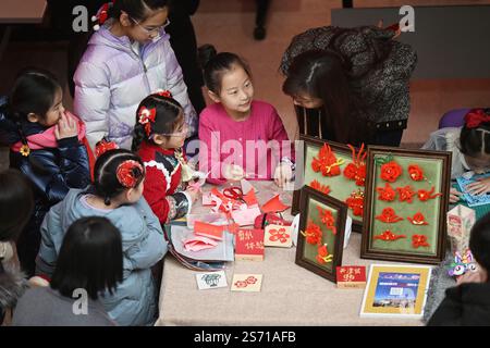Tianjin. 18 janvier 2025. Les enfants font l'expérience de la coupe de papier lors d'une foire du temple des enfants au Centre de la jeunesse et des enfants à Tianjin, dans le nord de la Chine, le 18 janvier 2025. L'événement pour enfants de trois jours a débuté samedi à Tianjin pour accueillir le nouvel an lunaire chinois en présentant le folklore du patrimoine culturel immatériel, des spectacles et des plats traditionnels. Crédit : Li Ran/Xinhua/Alamy Live News Banque D'Images