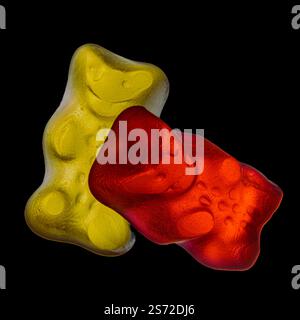 Une photo macro vibrante mettant en scène deux ours gommeux colorés, l'un en rouge et l'autre en jaune, sur fond noir. Banque D'Images