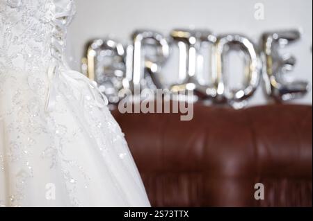 Un gros plan présente une superbe robe de mariée blanche ornée de dentelle complexe. La robe est élégamment affichée, avec un signe 'mariée' doucement hors fo Banque D'Images