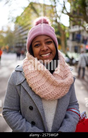 Portrait d'une jeune femme afro-américaine debout dehors en hiver, regardant la caméra souriant. Banque D'Images