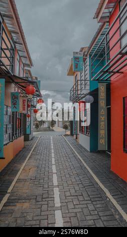 Une scène de rue colorée avec des bâtiments vibrants avec des panneaux en différentes langues. La rue est bordée de lanternes et a un ciel nuageux au-dessus de la tête, Banque D'Images