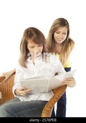 Deux jolies filles blondes souriantes lisant un livre, isolées sur fond blanc, Fédération de Russie Banque D'Images