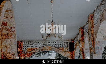 Un lustre vintage est suspendu à un plafond avec des arcades en marbre et des treillis complexes. Banque D'Images