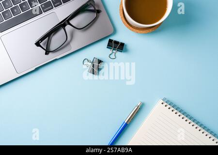 Tasse à café, clavier d'ordinateur portable et bloc-notes sur le bureau bleu. Concept de bureau d'affaires Banque D'Images