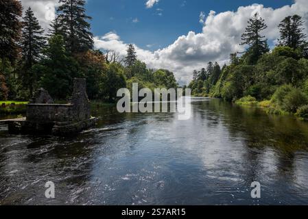 Vue sur la rivière Cong qui traverse le village de Cong, Irlande. Une petite cabane de pêcheur, se tient au bord de l'eau, entourée de verdure et calme ref Banque D'Images