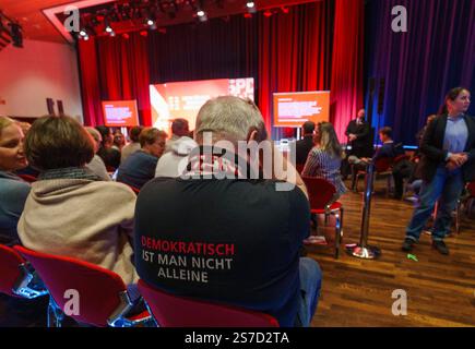 Schwalbach am Taunus, Allemagne. 19 janvier 2025. Lors de la campagne électorale du SPD organisée par le chancelier Scholz au Bürgerhaus, un participant porte une chemise avec le slogan "vous n'êtes pas seul en tant que démocrate". Le chancelier fédéral se rend en Hesse dans le cadre de la campagne électorale du Bundestag de 2025. L'élection anticipée au Bundestag allemand doit avoir lieu le 23 février 2025. Crédit : Andreas Arnold/dpa/Alamy Live News Banque D'Images