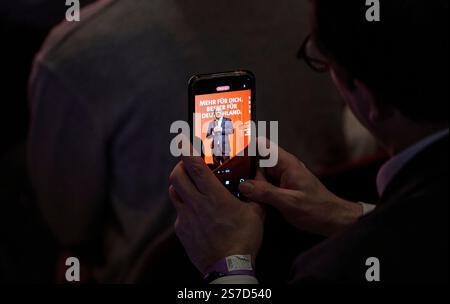 Schwalbach am Taunus, Allemagne. 19 janvier 2025. OLAF Scholz (SPD), chancelier fédéral et candidat principal de son parti, peut être vu sur un smartphone lors de la campagne électorale dans le Bürgerhaus. La chancelière se rend en Hesse dans le cadre de la campagne électorale du Bundestag de 2025. Le centre communautaire de Schwalbach est complet. L'élection anticipée au Bundestag allemand doit avoir lieu le 23 février 2025. Crédit : Andreas Arnold/dpa/Alamy Live News Banque D'Images