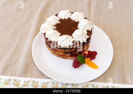 Un gâteau superposé magnifiquement présenté, garni de crème fouettée et entouré de fruits frais. Ce dessert est parfait pour les occasions spéciales ou un délire Banque D'Images