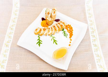 Un plateau de sushis magnifiquement arrangé avec divers rouleaux, des légumes colorés et un filet de sauce. La présentation est attrayante et marquante Banque D'Images