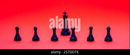 Les pièces d'échecs noires, y compris un roi et des pions, sont positionnées sur un fond rouge vif. L'arrangement signifie un jeu réfléchi en cours, évoquant Banque D'Images