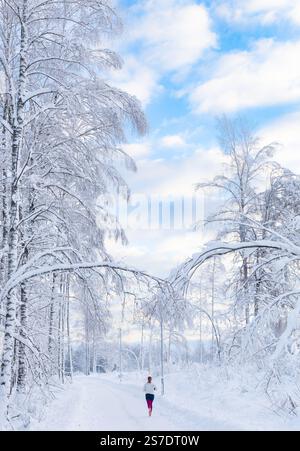 Jeune femme faisant du jogging dans un paysage enneigé par une belle journée d'hiver à Raasepori, dans le sud de la Finlande Banque D'Images