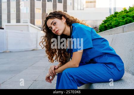 Belle jeune infirmière portant l'uniforme bleu de l'hôpital se promenant dans la ville - femme caucasienne joyeuse médecin allant travailler à l'hôpital Banque D'Images