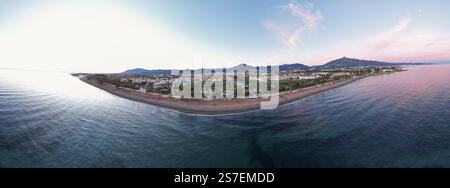 Panorama aérien lumineux et coloré de coucher de soleil avec un soleil brillant et un ciel vibrant entourant la côte méditerranéenne de Marbella en Espagne Banque D'Images